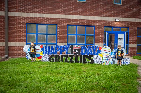 two boys in front of happy first day grizzlies sign